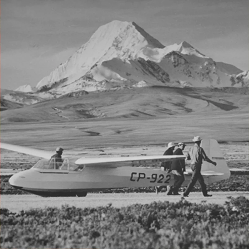 Planeador CP-922 junto a dos personas en una pista del altiplano, con un nevado al fondo.