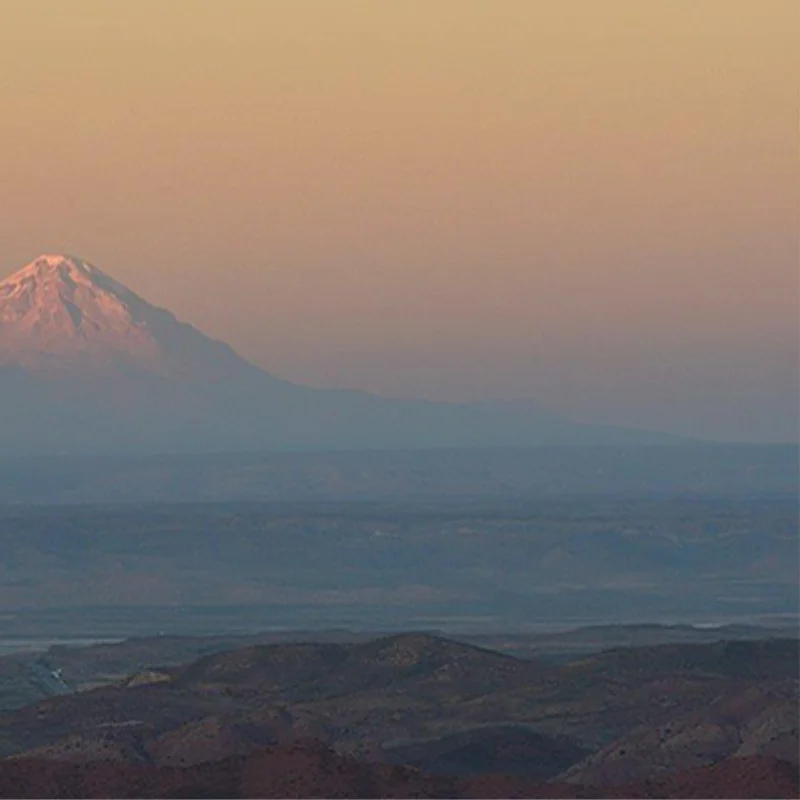 Nevado iluminado por la luz rosada del atardecer sobre el paisaje altiplánico.